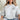 Great Pyrenees Unisex light gray sweatshirt modeled by a woman sitting on a couch in a living room.