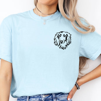 Light blue long haired dachshund t-shirt modeled by a woman standing in front of a white backdrop.