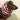 Red, blue, and tan striped dog snood worn by a Dachshund.